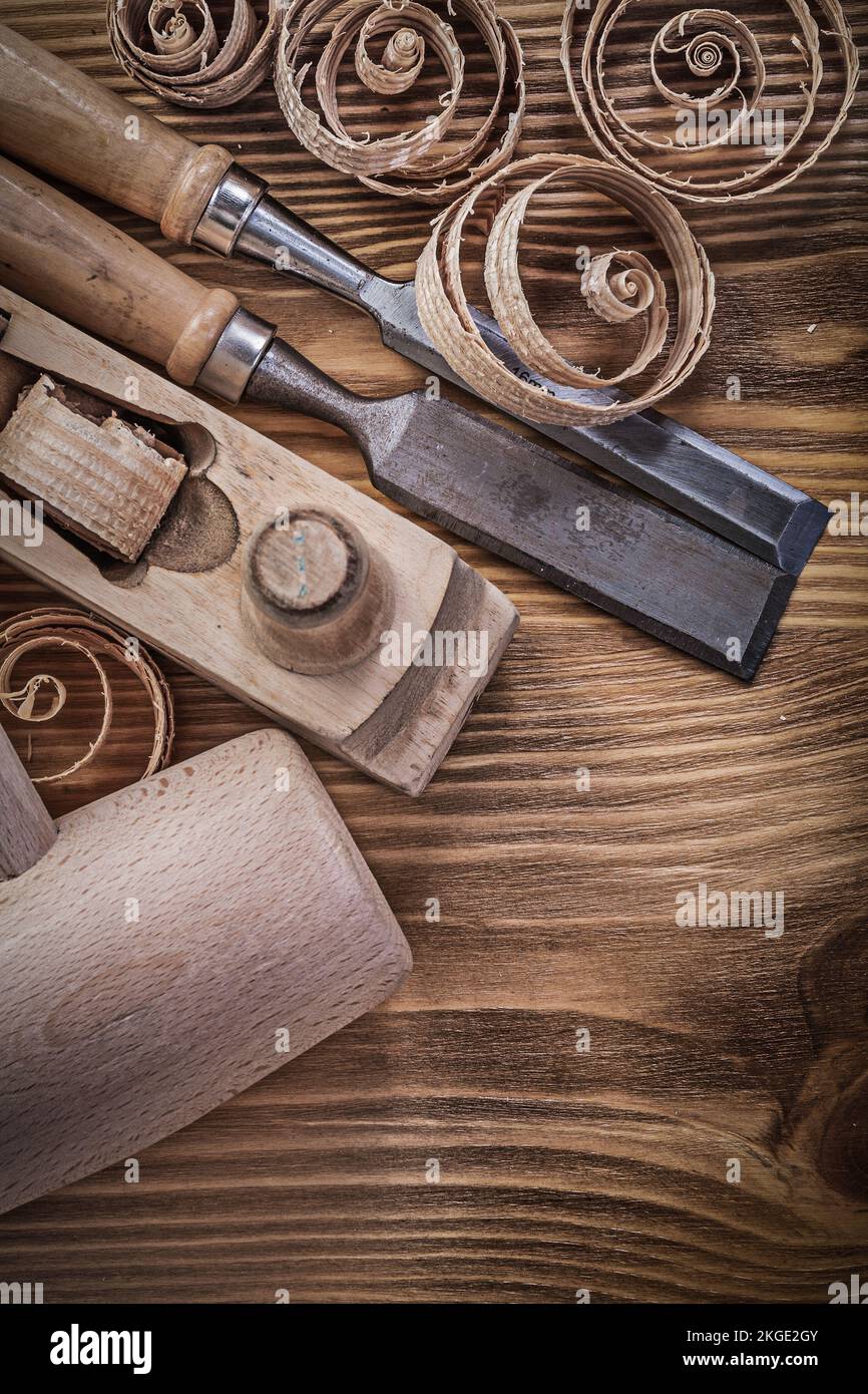 Firmer chisels shaving plane curled shavings wooden mallet on wood board construction concept. Stock Photo