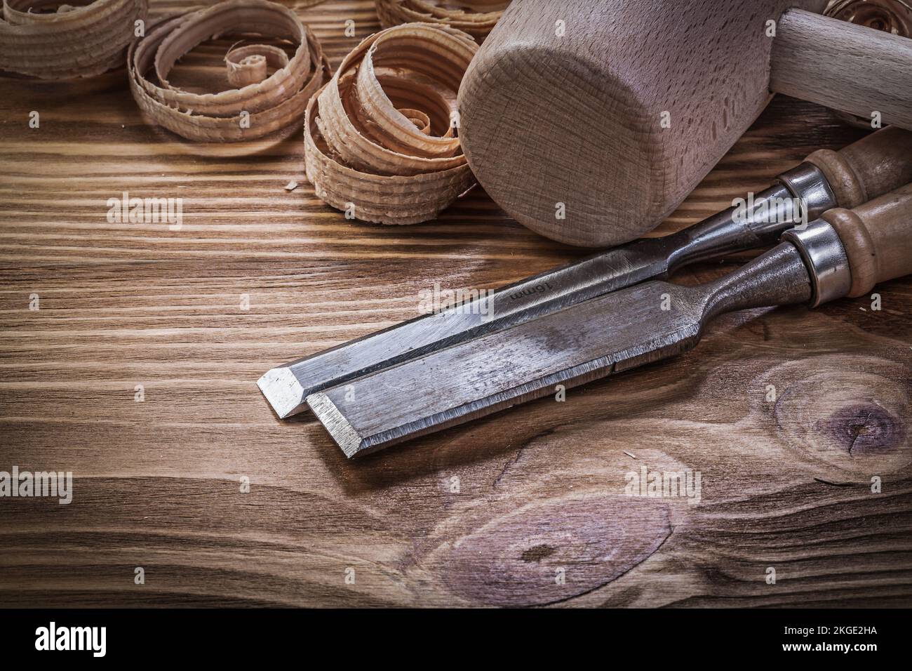 Flat chisels curled shavings wooden hammer on wood board construction concept. Stock Photo