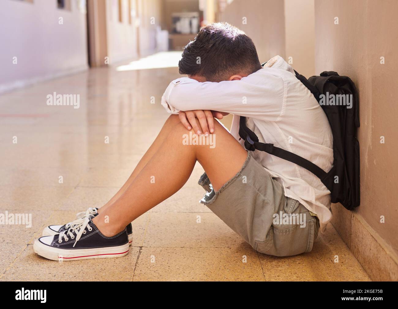 Anxiety, school and sad student bullying victim feeling depression, lost or stressed in hallway or corridor floor. Child, depressed boy or lonely male Stock Photo