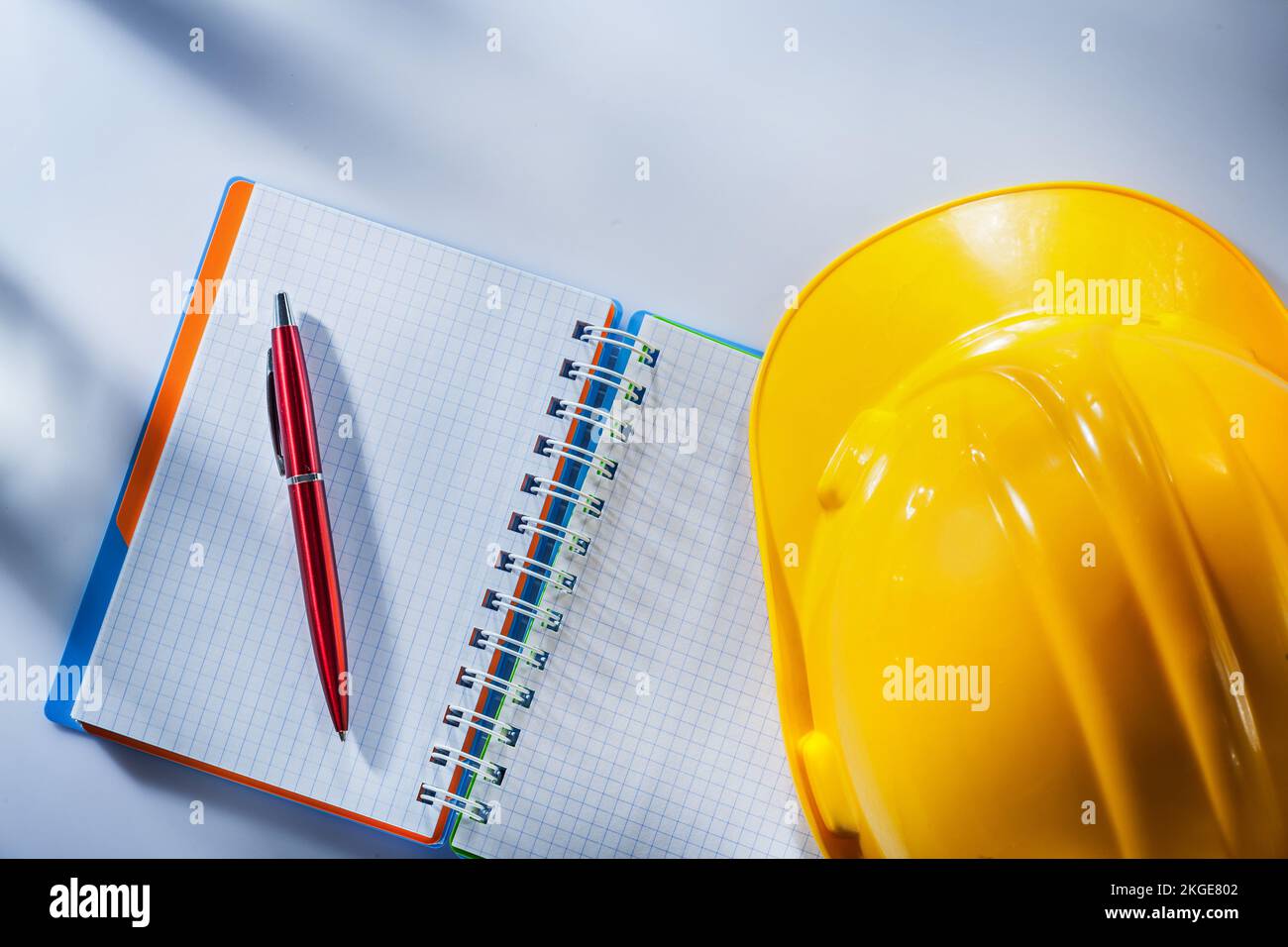 Hard hat checked notepad pen on white background. Stock Photo