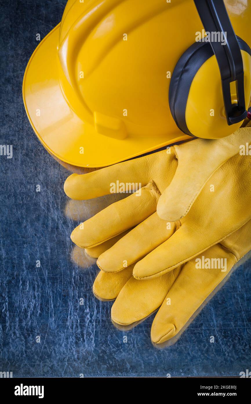 Hard hat safety earmuffs and yellow leather protective gloves on