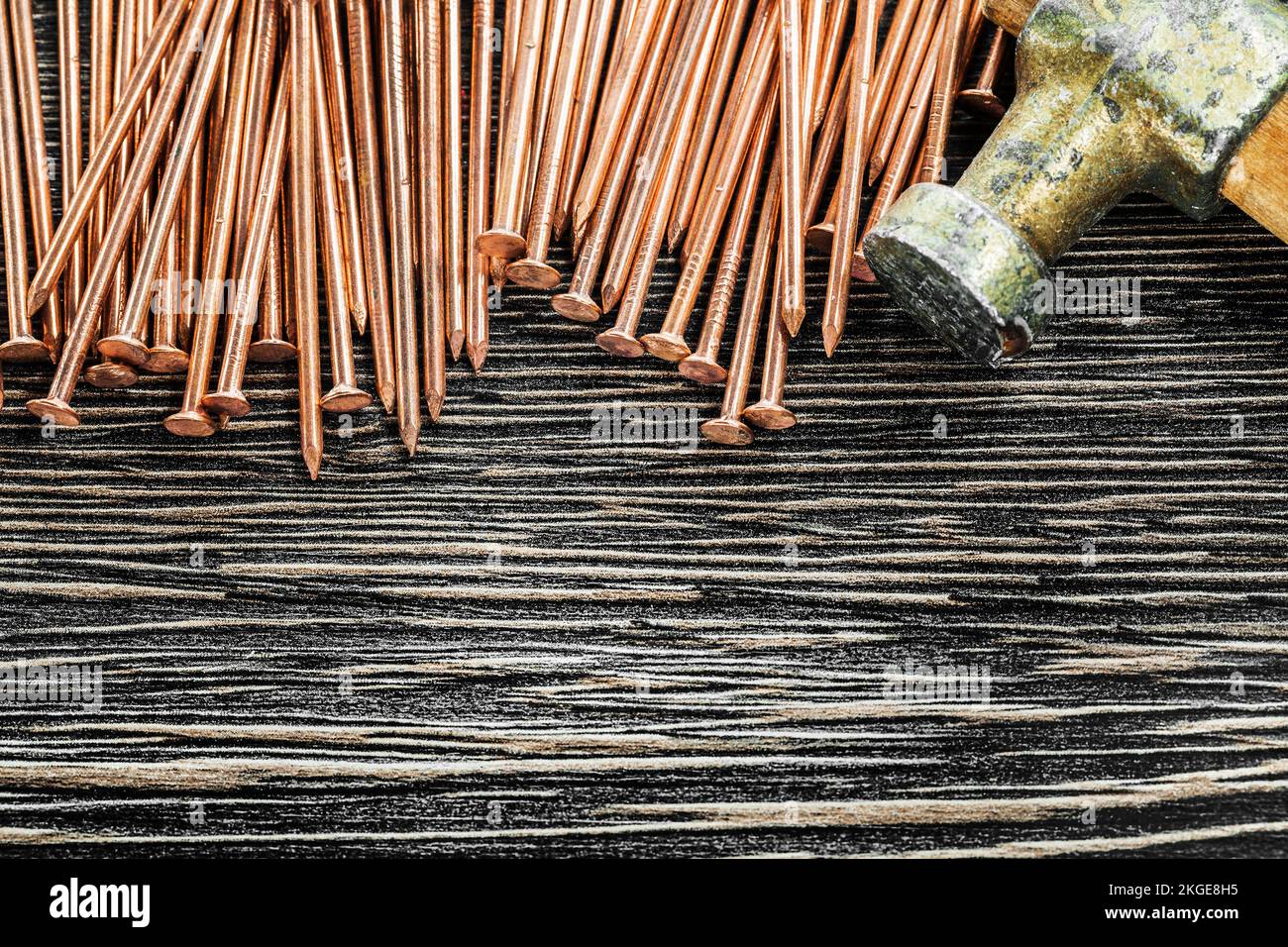 Heap of copper nails claw hammer on wooden board. Stock Photo