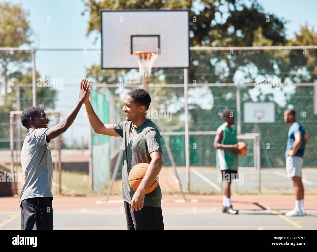 Basketball court, high five and team sports, success and support, winners and achievement outdoor. Excited basketball player community, men and Stock Photo
