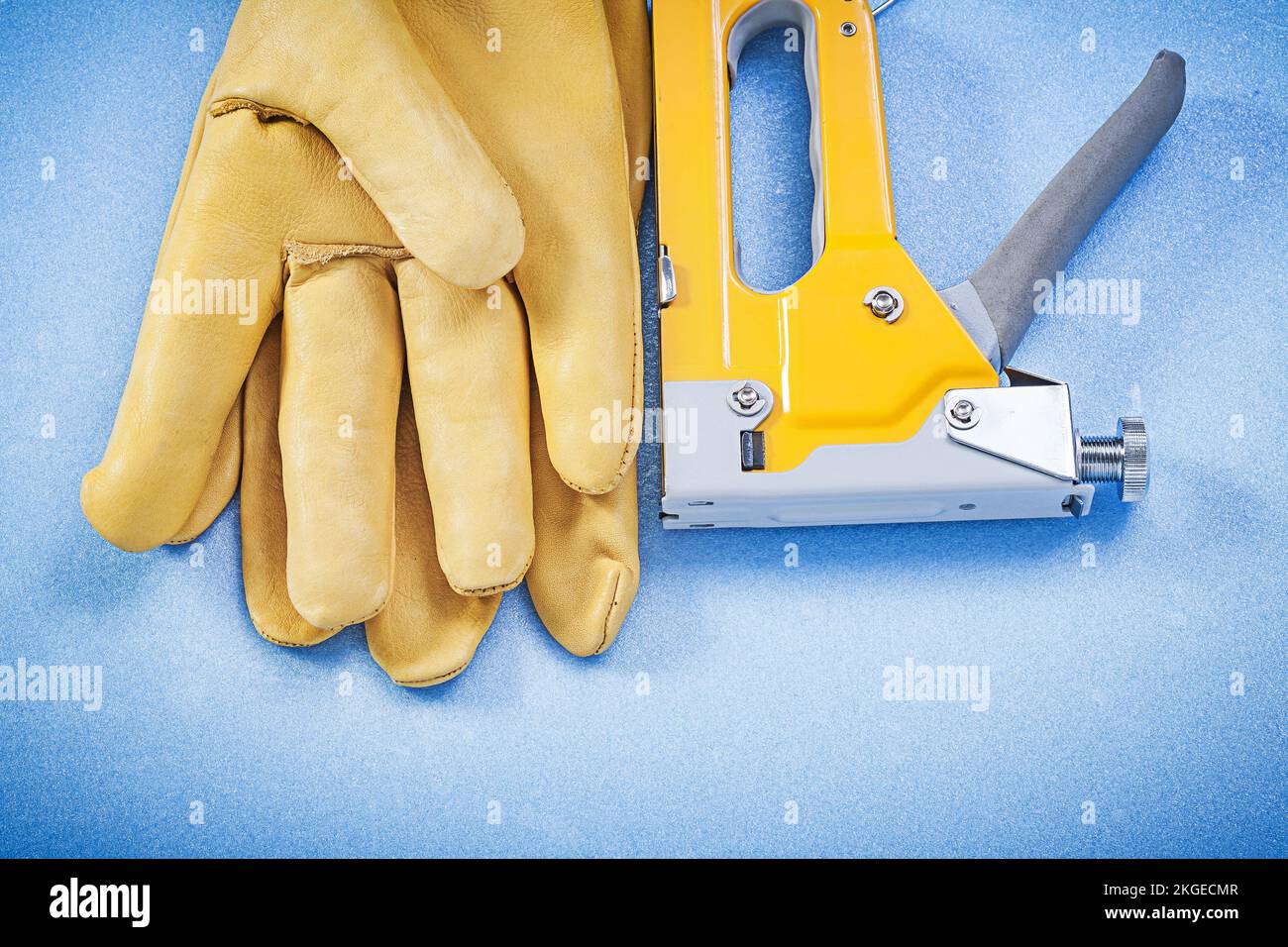 Leather working gloves yellow construction staple on blue background top view. Stock Photo