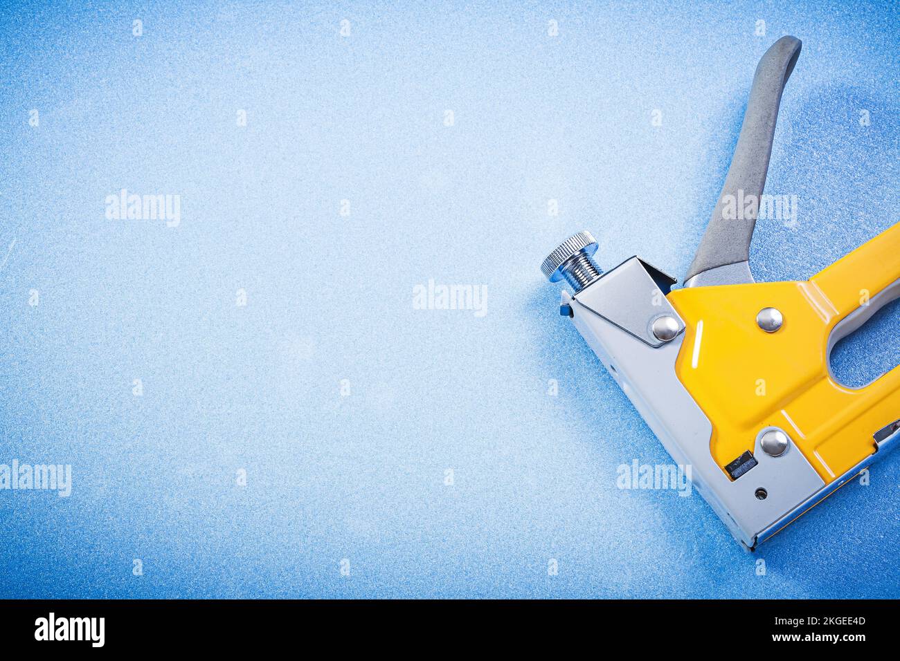 Metal staple gun on blue background construction concept. Stock Photo