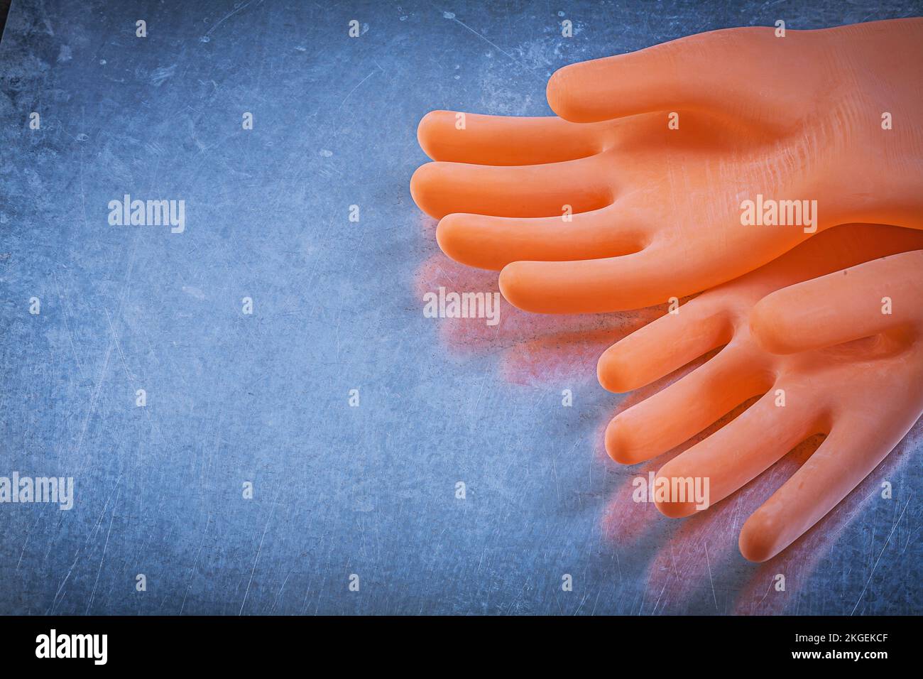 Pair of dielectric rubber gloves on metallic background electricity