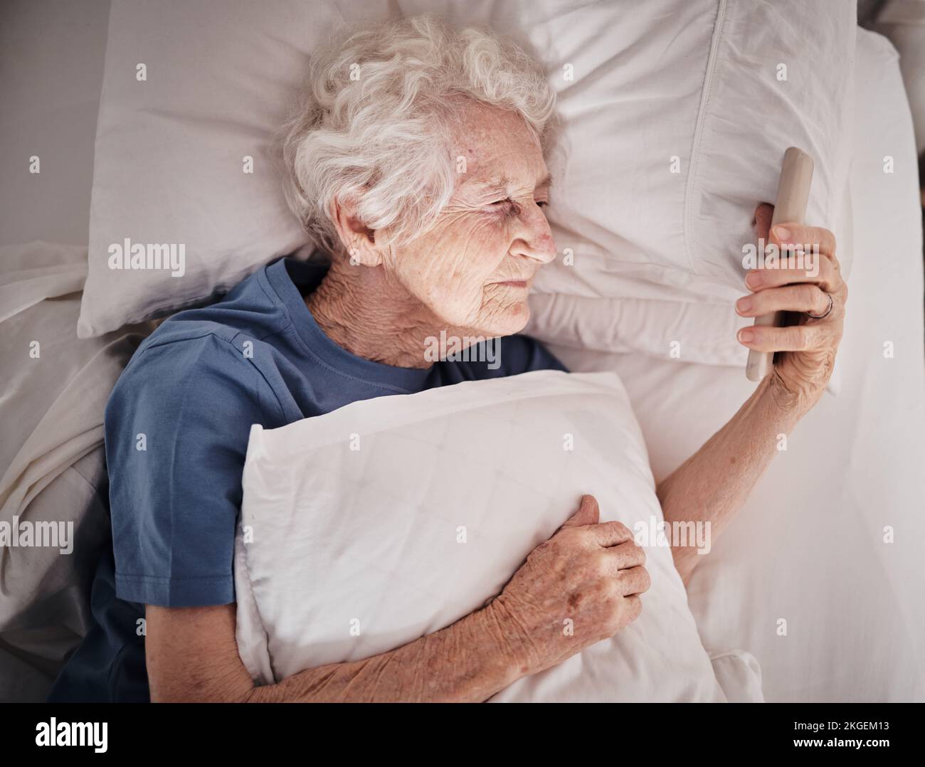 Bad vision, senior woman and phone on bed in bedroom home texting, social media or internet browsing. Blurred eyesight, retired and elderly female Stock Photo
