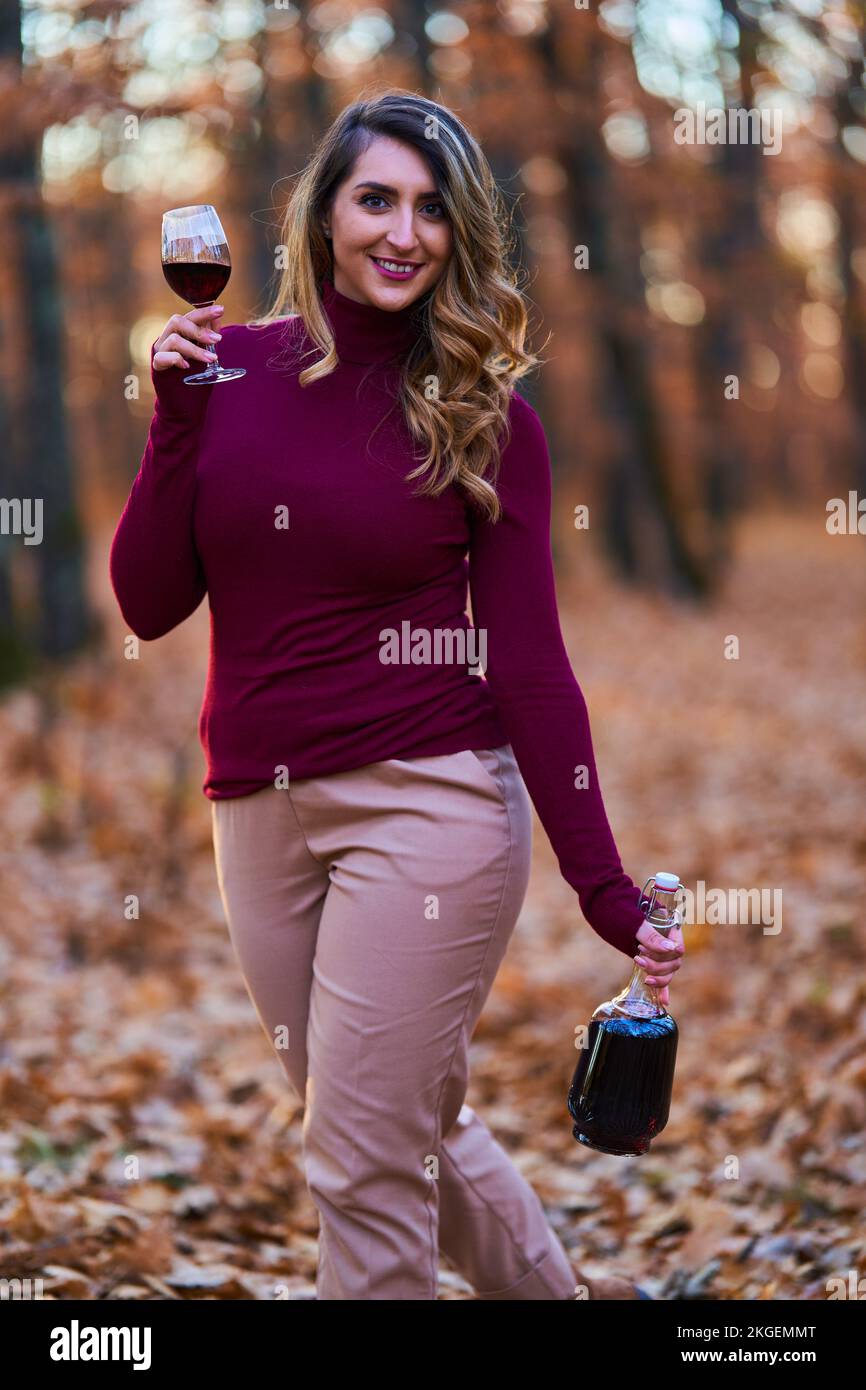 Beautiful plus size young indian woman enjoying a glass of red wine in the oak forest at sunset Stock Photo