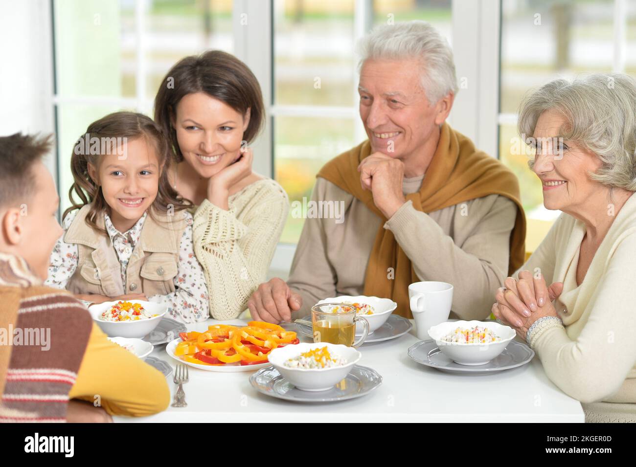 Happy family of different generations eating together Stock Photo - Alamy