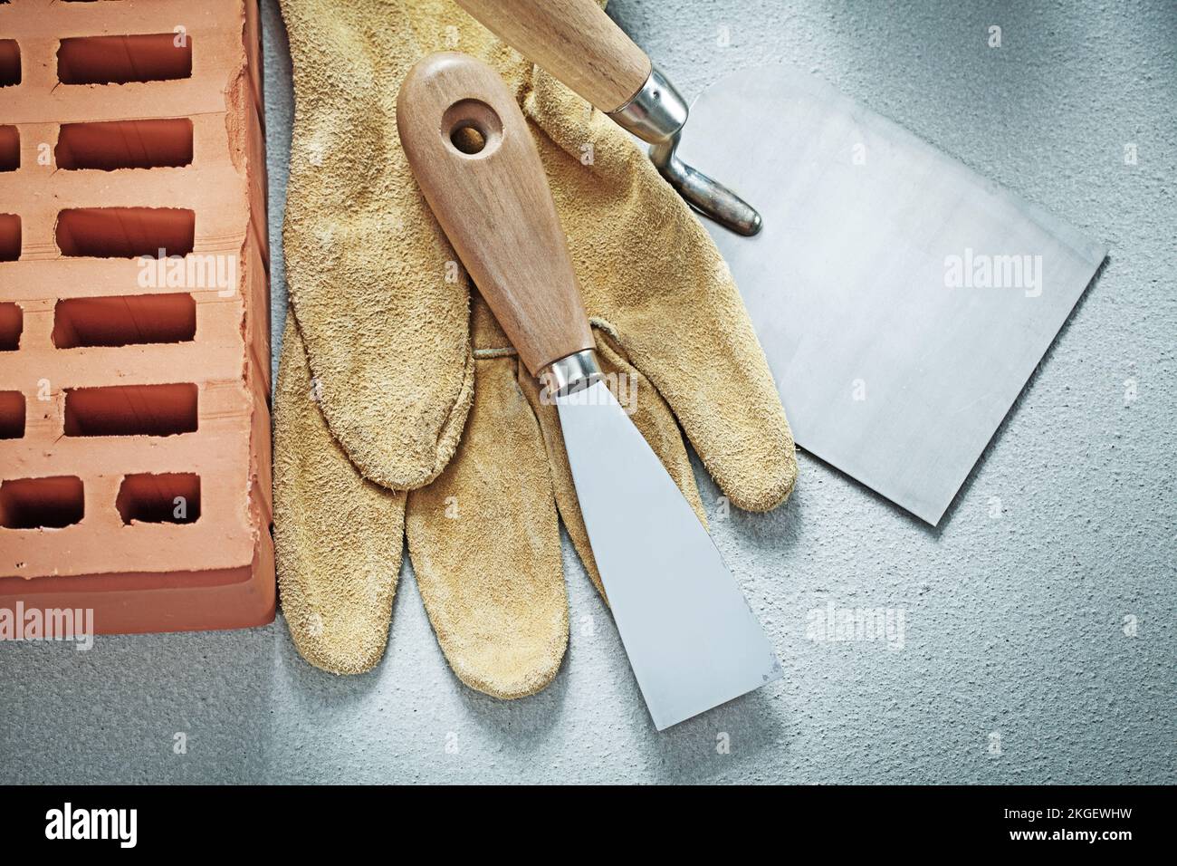 Red brick safety gloves paint scrapers on concrete surface bricklaying