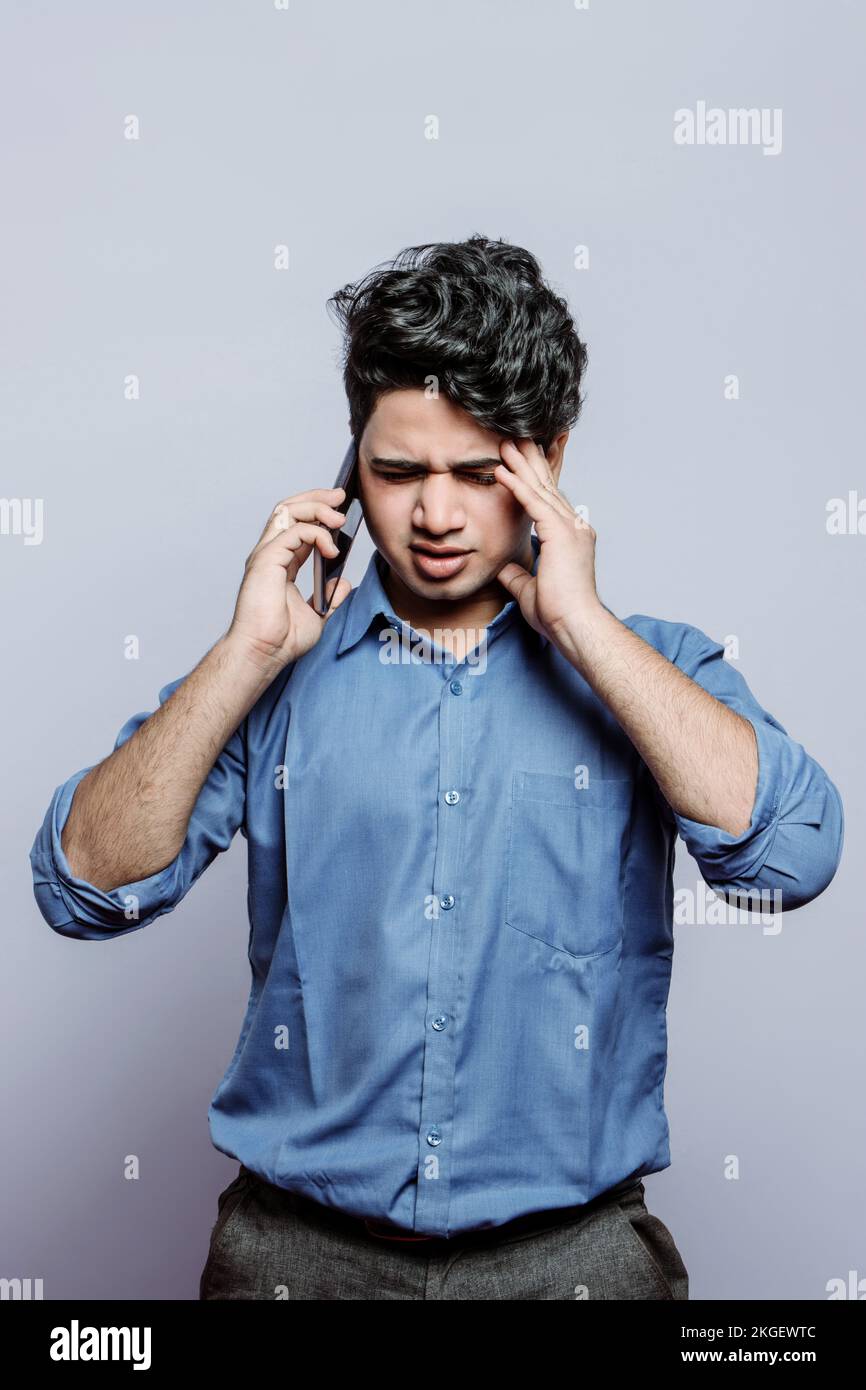 Worried middle-aged man having conversation on smartphone, touching his head. How to improve your memory. A young man managing critical relationship. Stock Photo
