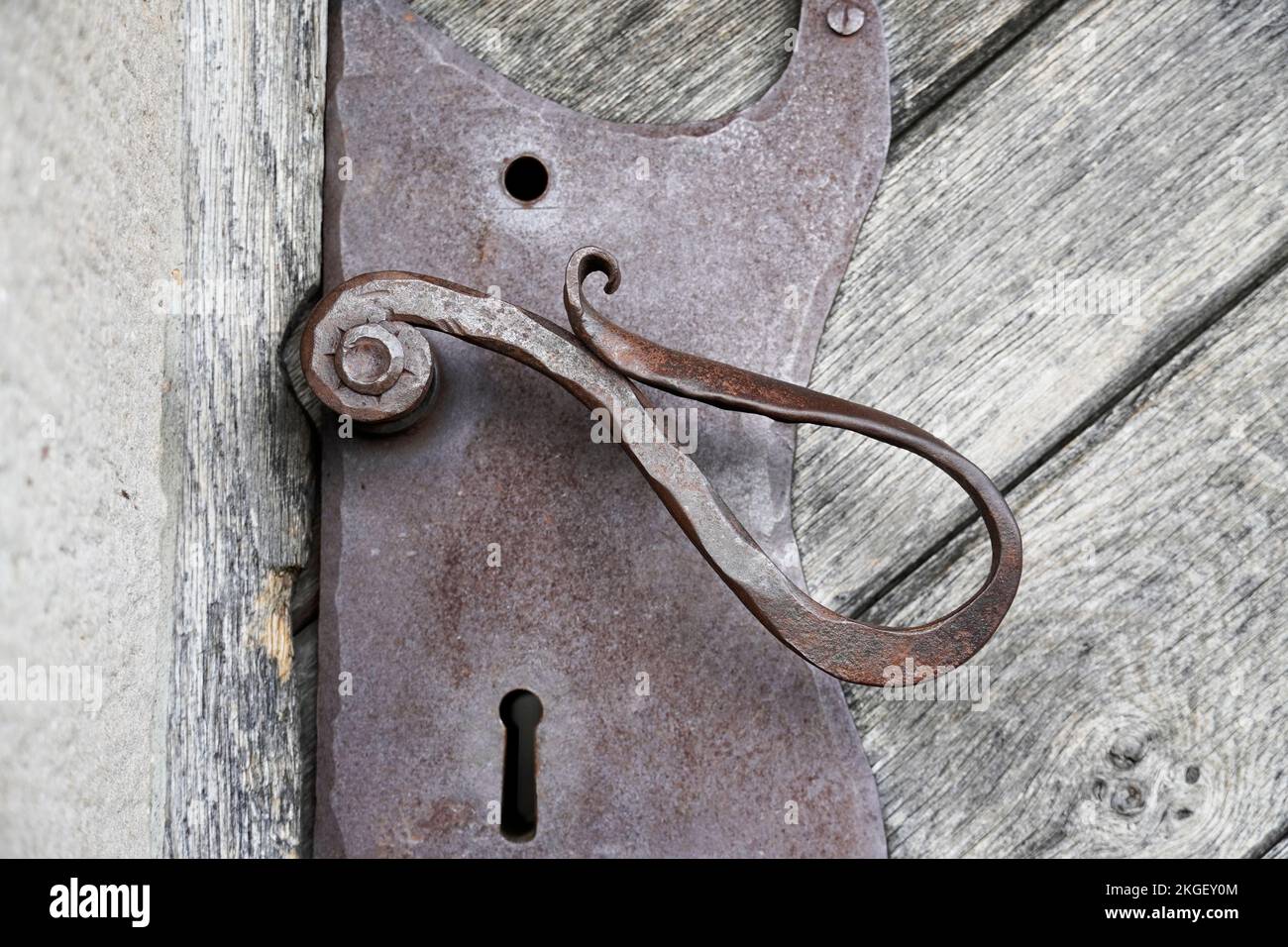 Old forged metal door handle on a wooden door of a historic castle. Stock Photo