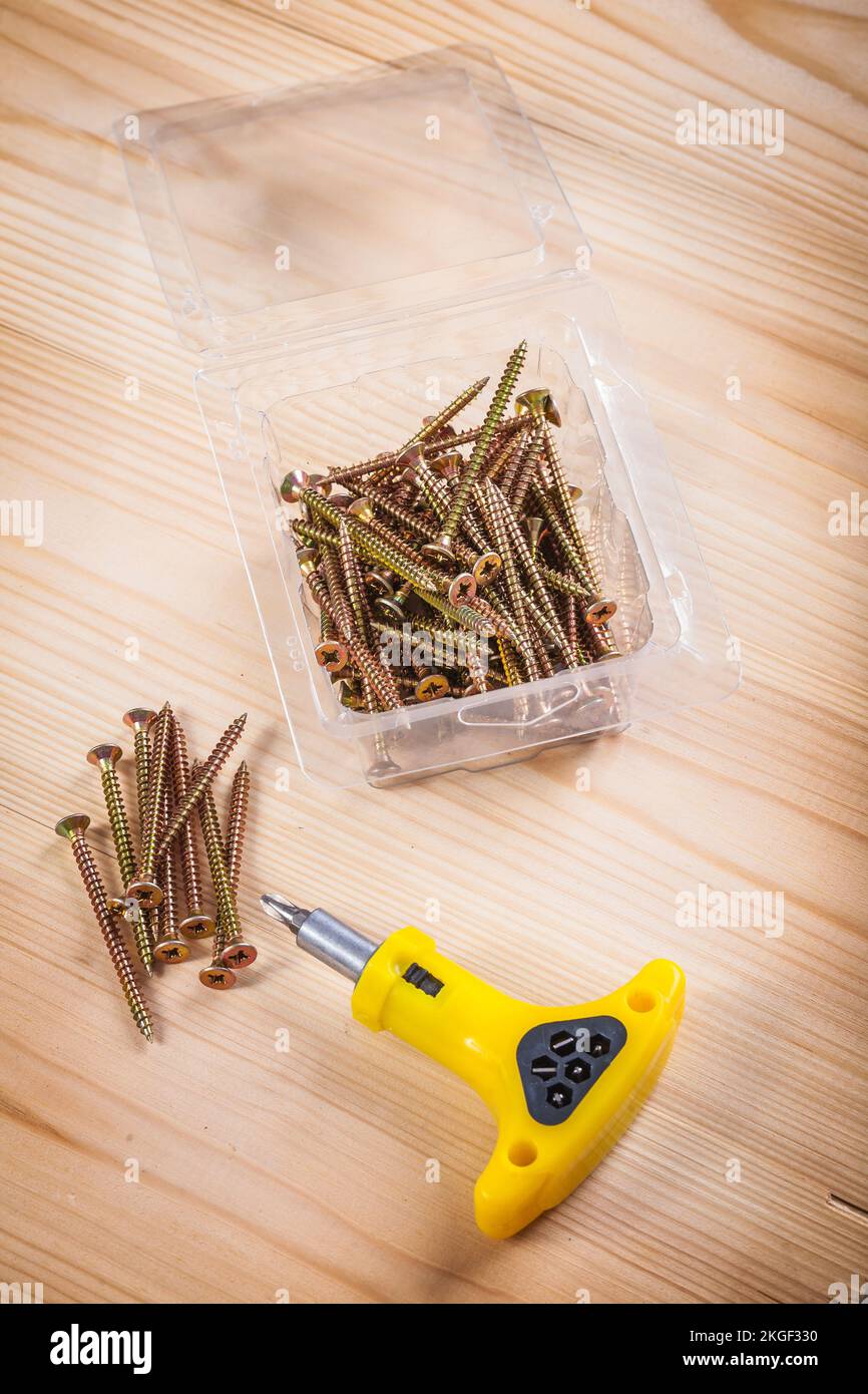 screws and screwdriver on wooden board Stock Photo