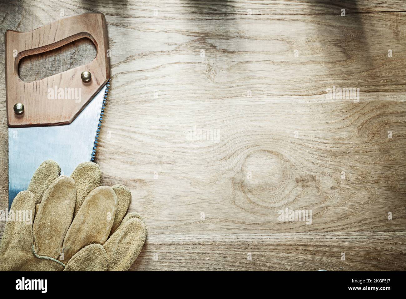Set of safety gloves stainless handsaw on wood board construction ...