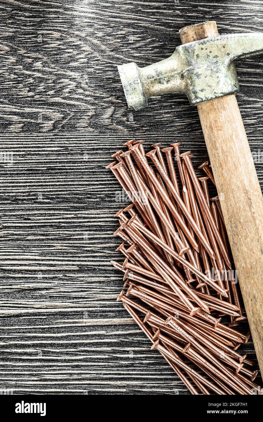 Stack of copper nails claw hammer on wooden board. Stock Photo