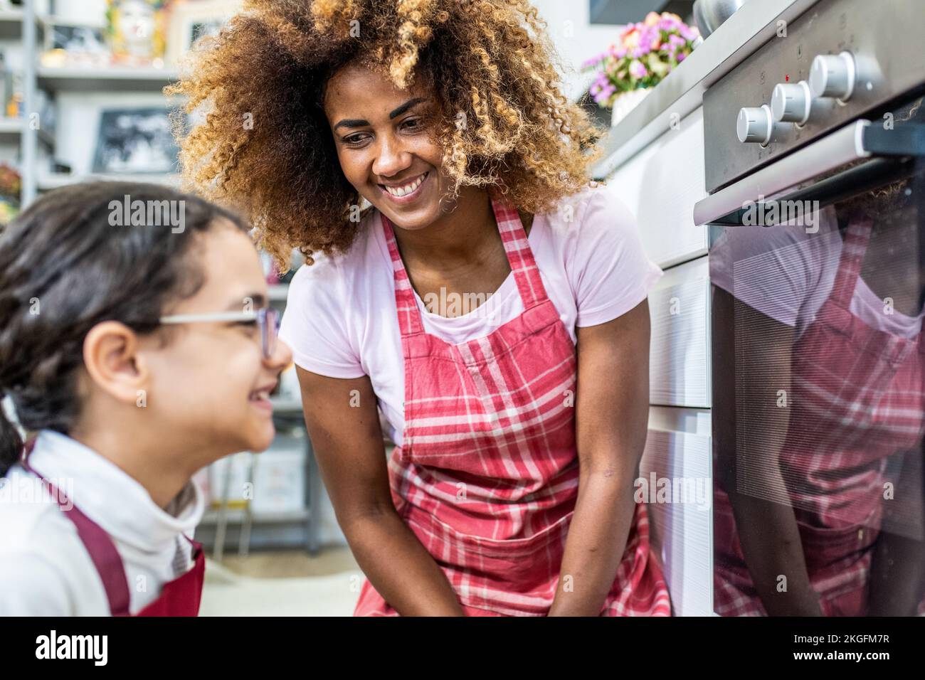 lovely scene of a mother and daughter preparing food in the kitchen, multiracial family cooking at home Stock Photo