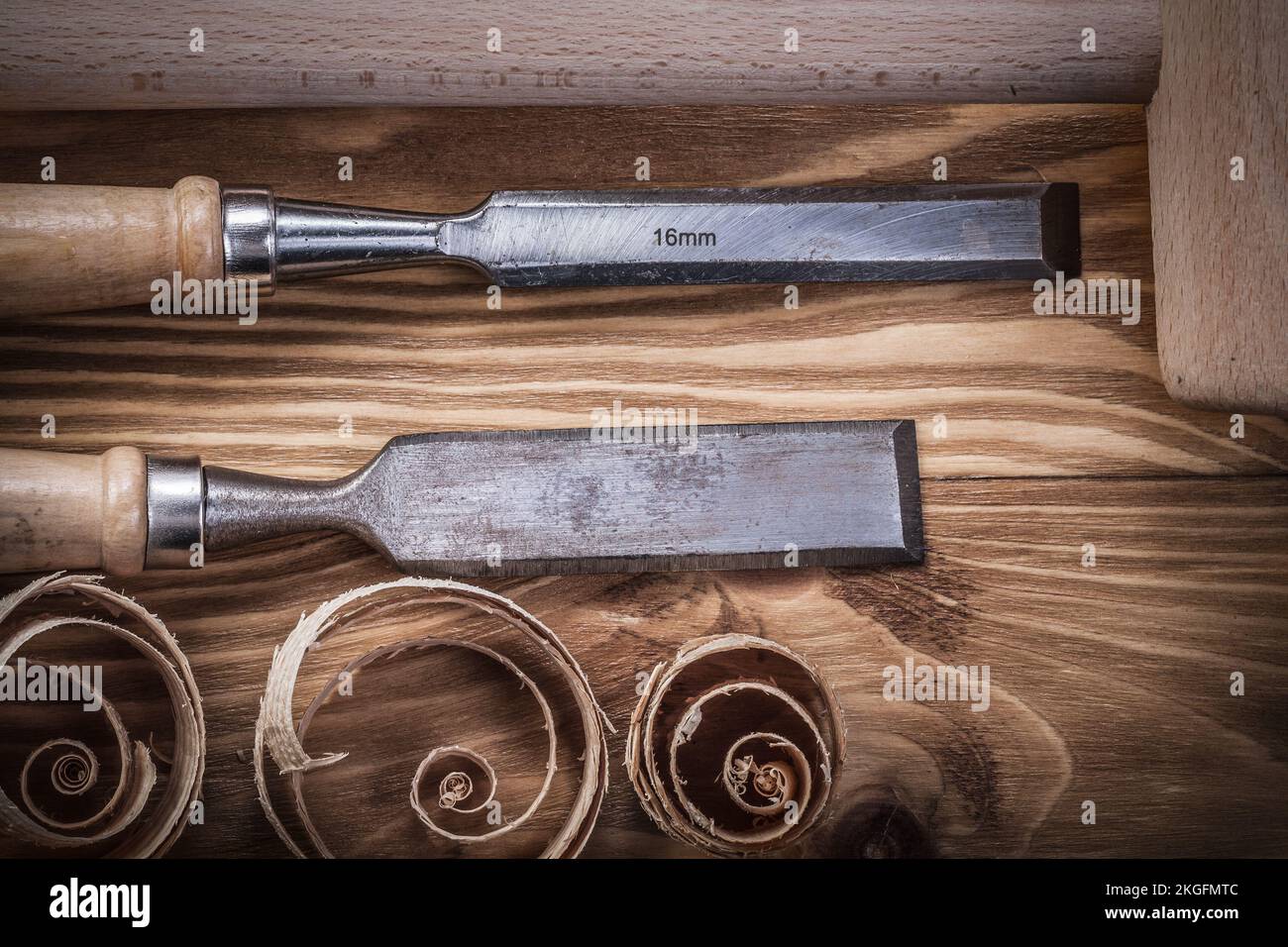 Wooden hammer flat chisels planning chips on vintage wood board construction concept. Stock Photo