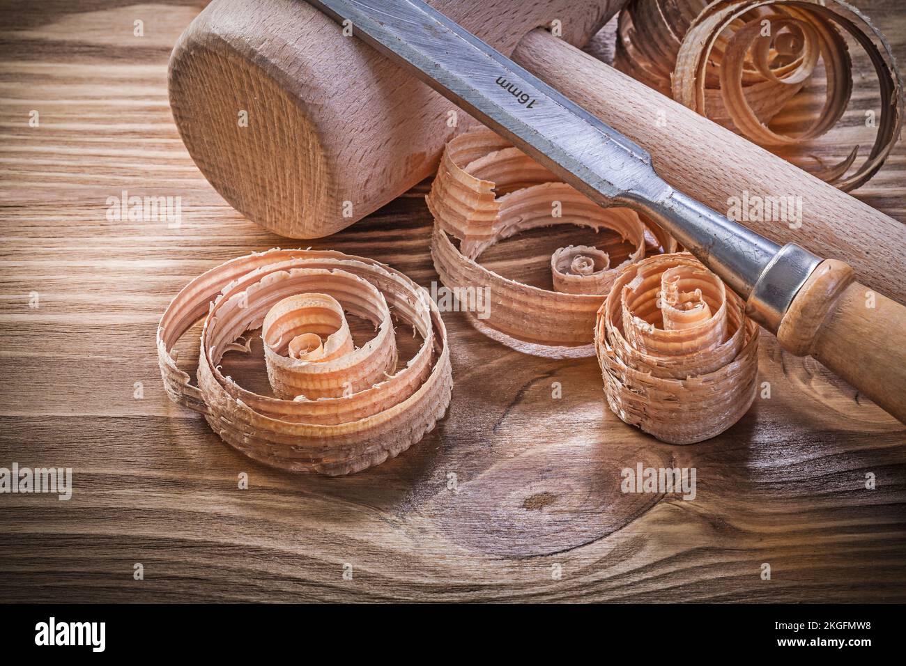 Wooden mallet flat chisels curled shavings on vintage wood board construction concept. Stock Photo