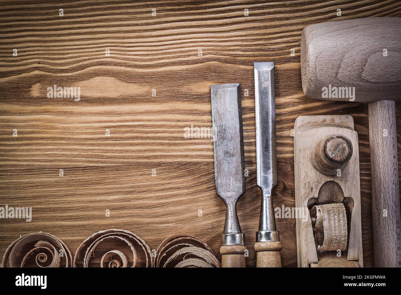 Wooden hammer planer chisels curled shavings on vintage wood board construction concept. Stock Photo