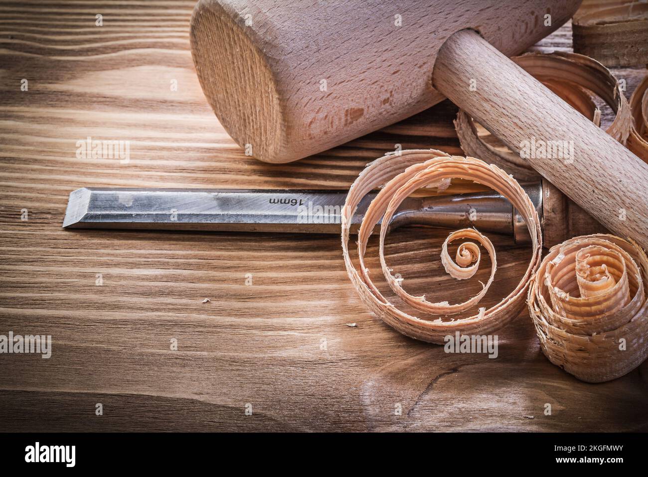 Wooden mallet firmer chisels curled shavings on vintage wood board construction concept. Stock Photo
