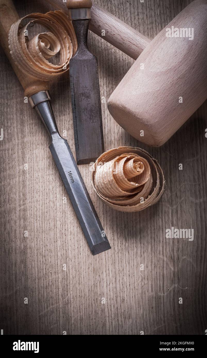 Wooden mallet curled up shavings flat chisels on wood board construction concept. Stock Photo