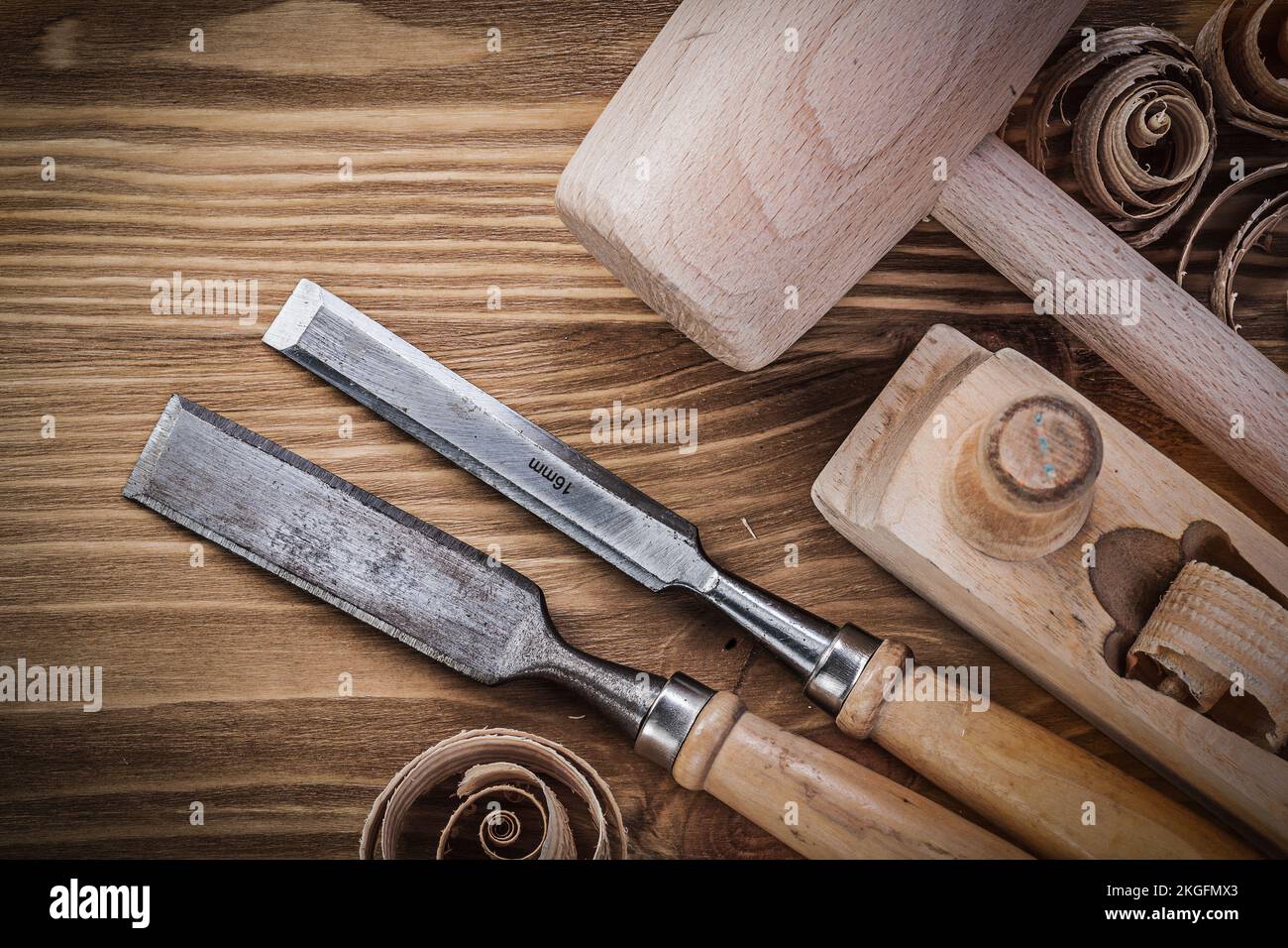 Wooden mallet planer flat chisels curled shavings on vintage wood board construction concept. Stock Photo