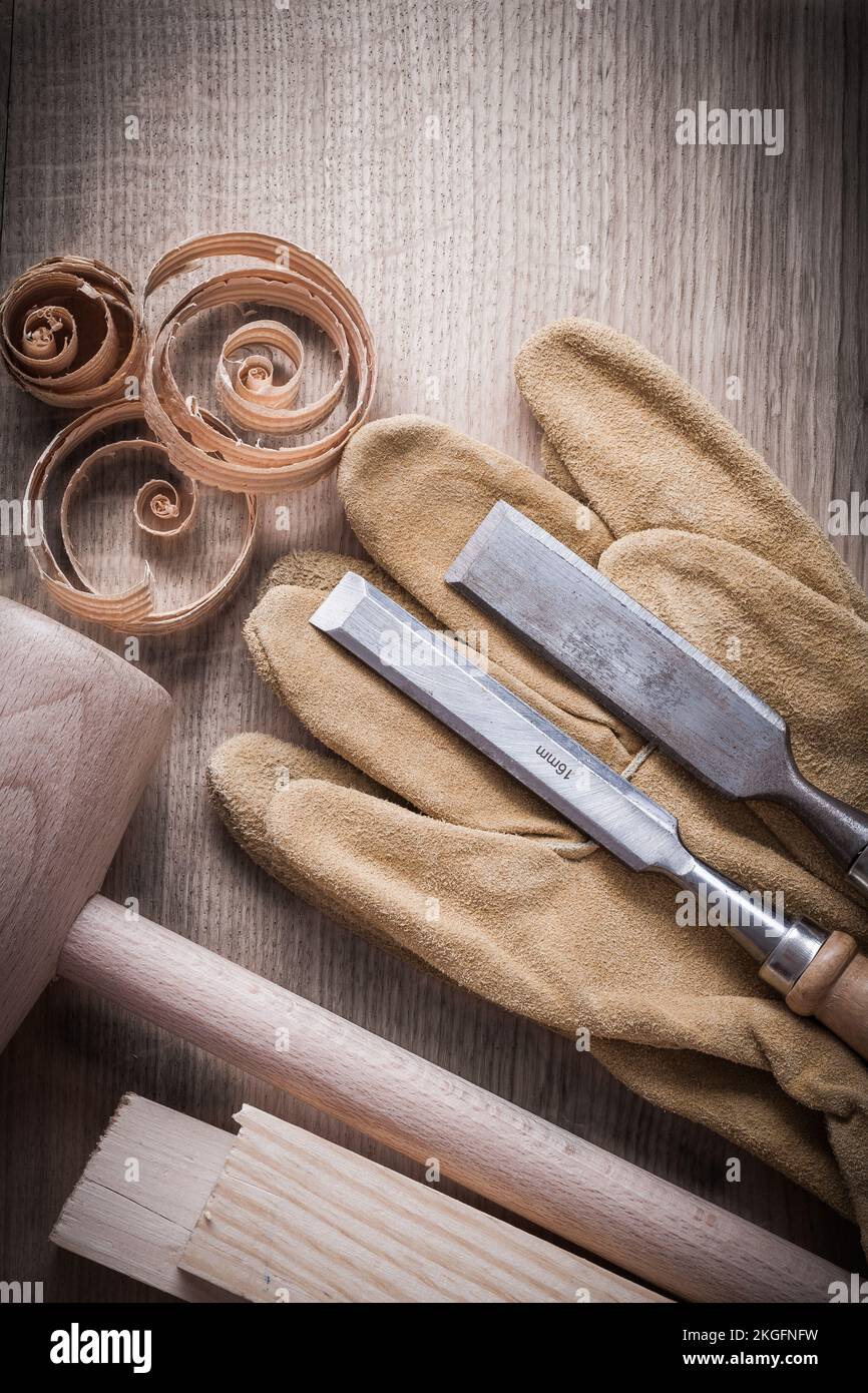 Wooden planks hammer curled up shavings firmer chisels leather gloves on wood board construction concept. Stock Photo