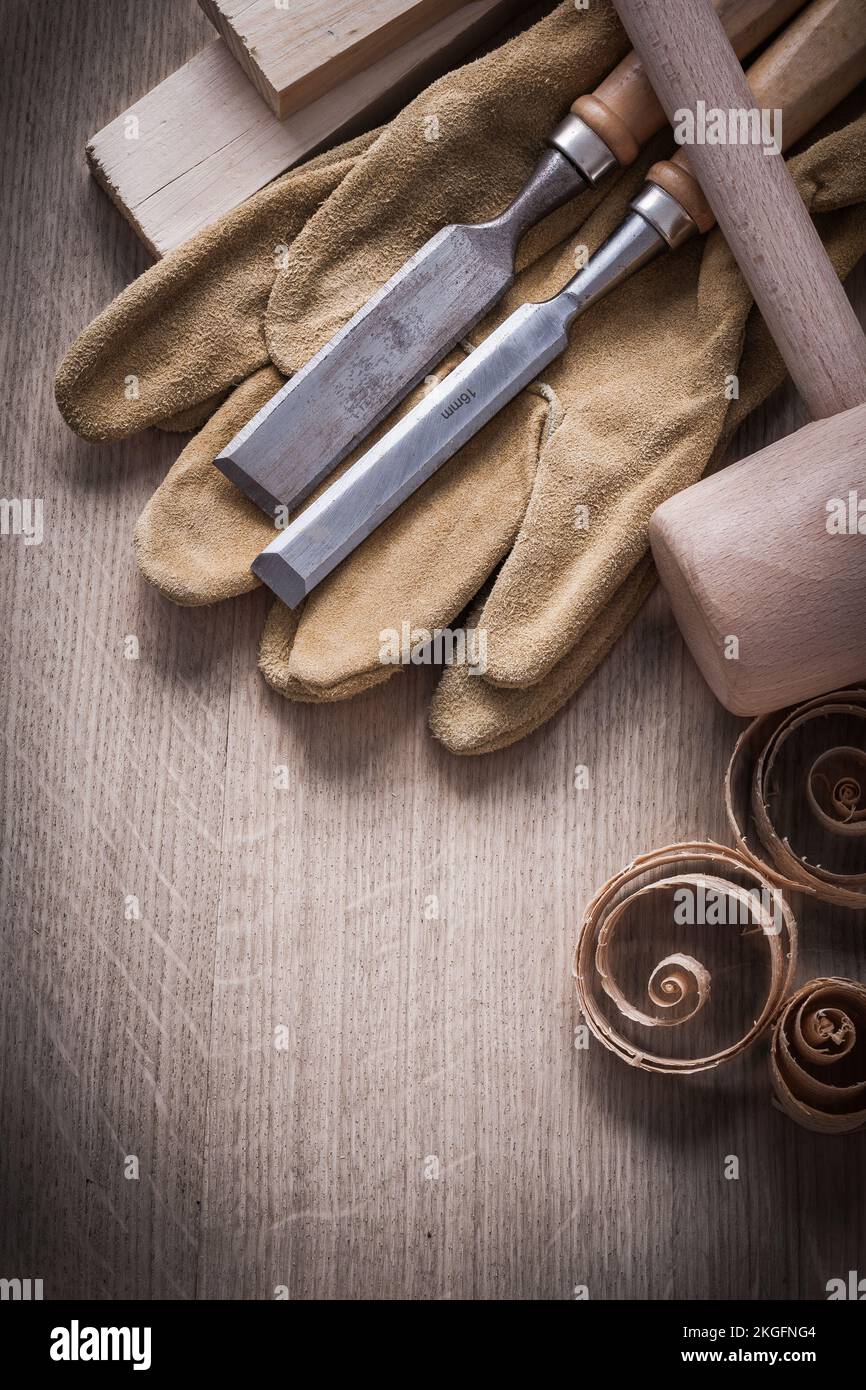 Wooden planks hammer curled up shavings flat chisels leather working gloves on wood board construction concept. Stock Photo