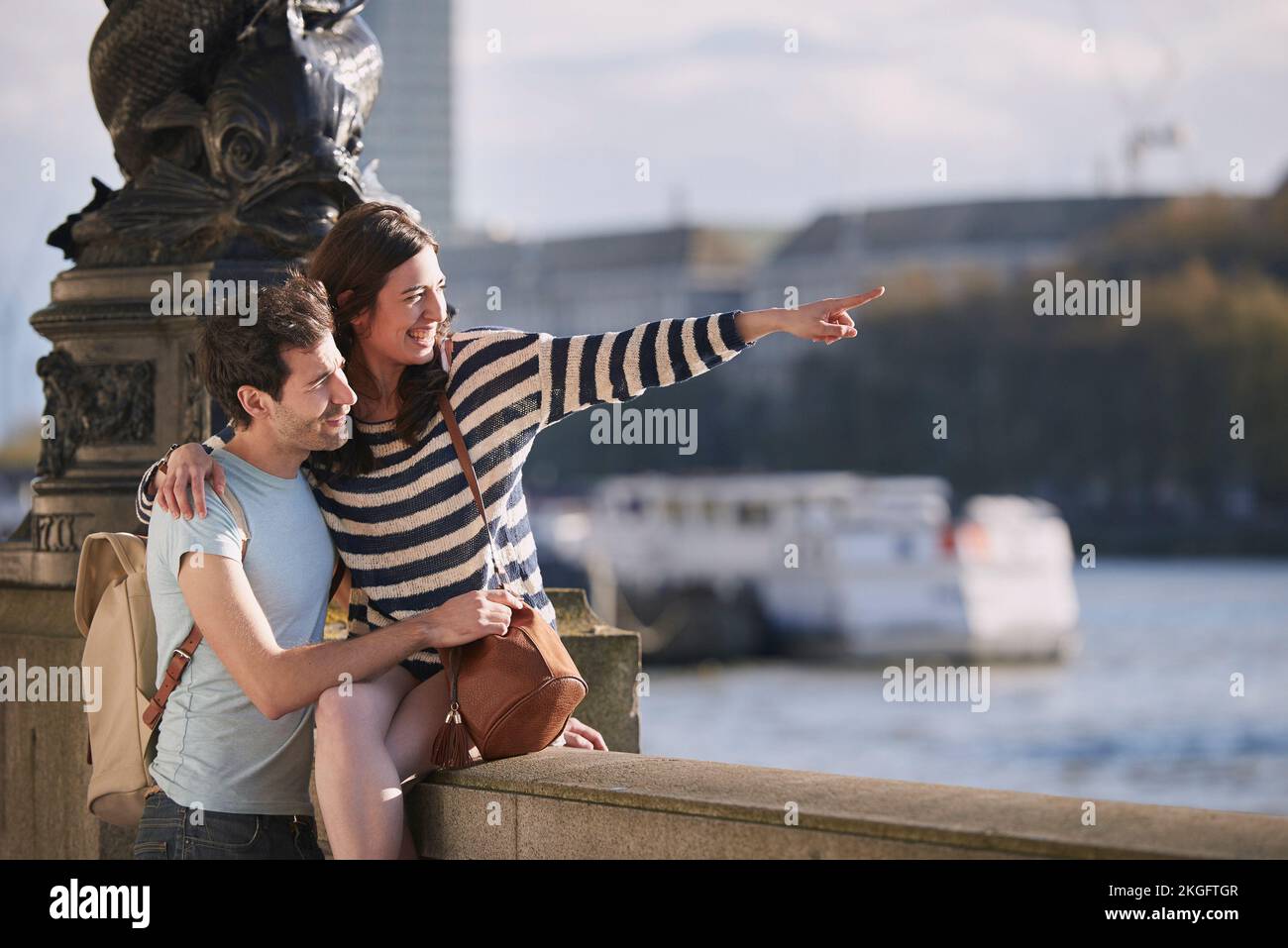 Travel, love and honeymoon with a young couple pointing while sightseeing on an overseas trip abroad together. Water, city and summer with a man and Stock Photo
