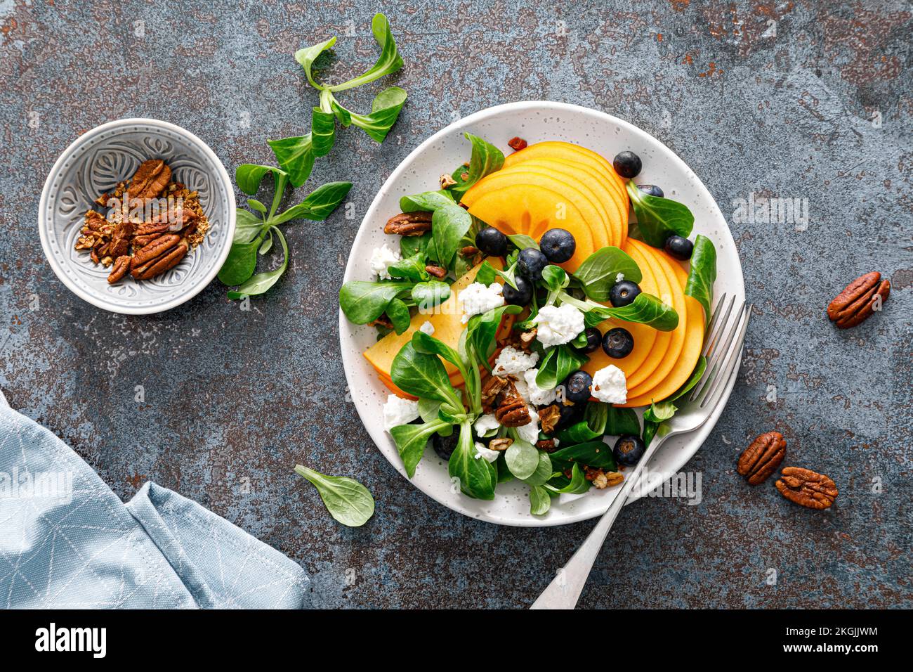 Persimmon fruit salad with blueberry, pecan nuts and ricotta chesse. Healthy food. Top view Stock Photo