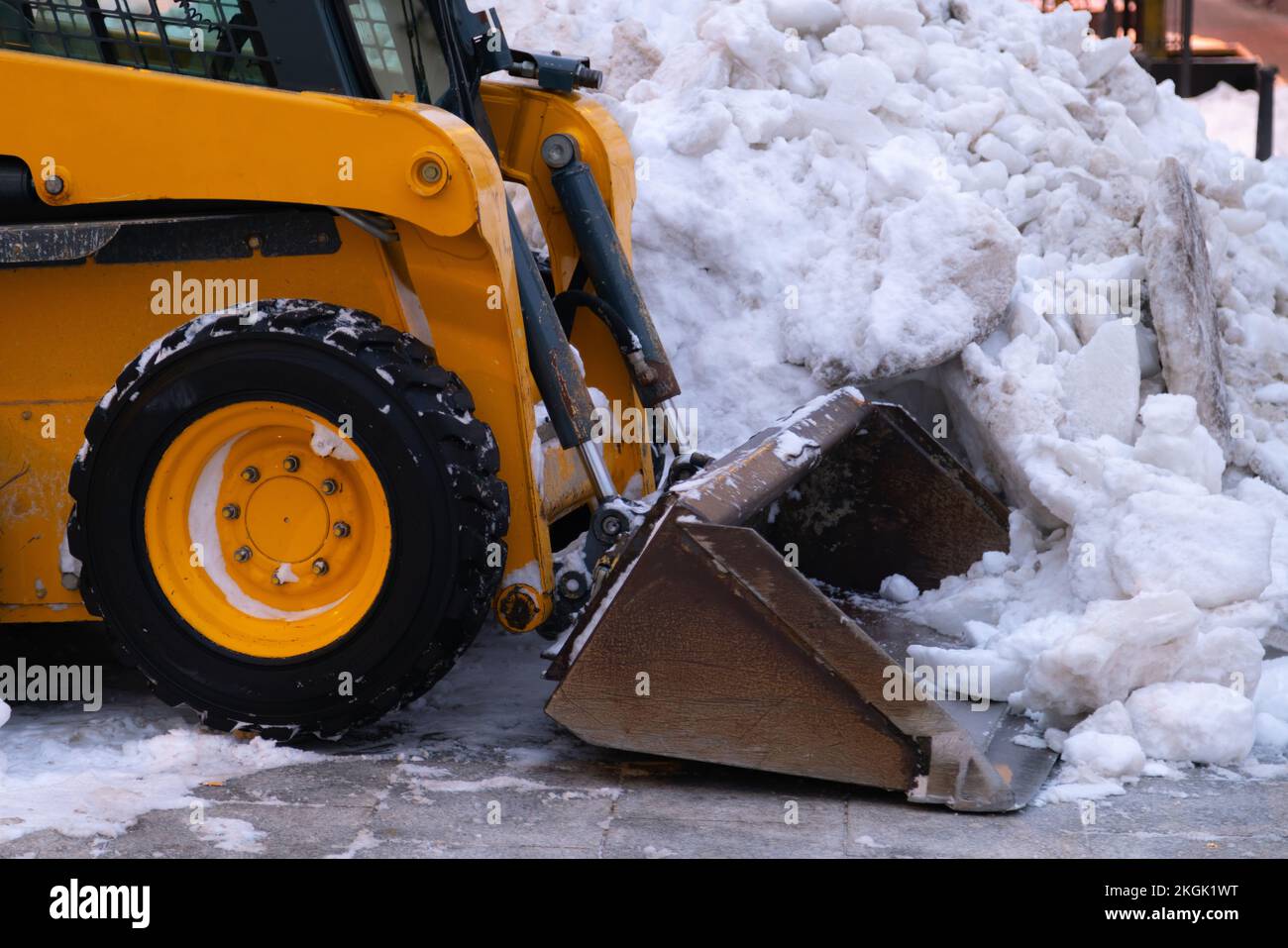 Heavy duty earth mover cleaning snow off the sidewalks after blizzard. Stock Photo