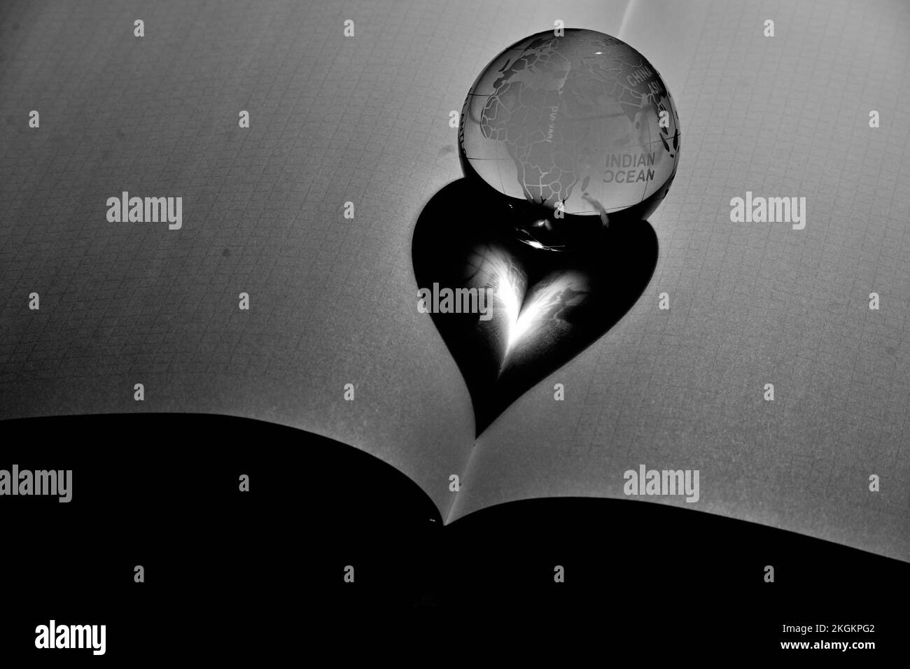 A grayscale shot of a crystal globe shaped ball with a heart reflection Stock Photo
