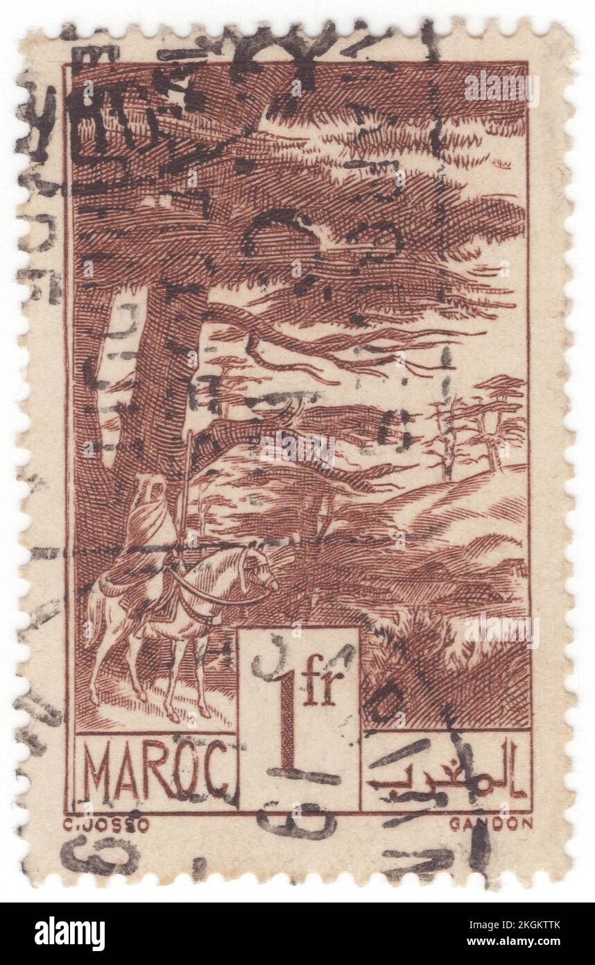 FRENCH MOROCCO - 1939: An 1 franc chocolate postage stamp depicting Cedars (Juniperus oxycedrus, vernacularly called Cade, cade juniper, prickly juniper, prickly cedar, or sharp cedar), is a species of juniper, native across the Mediterranean region from Algeria and Portugal, north to southern France, east to westernmost Iran, and south to Lebanon and Israel, growing on a variety of rocky sites from sea level up to 1,600 metres in elevation. The specific epithet oxycedrus means 'sharp cedar' and this species may have been the original cedar or cedrus of the ancient Greeks Stock Photo