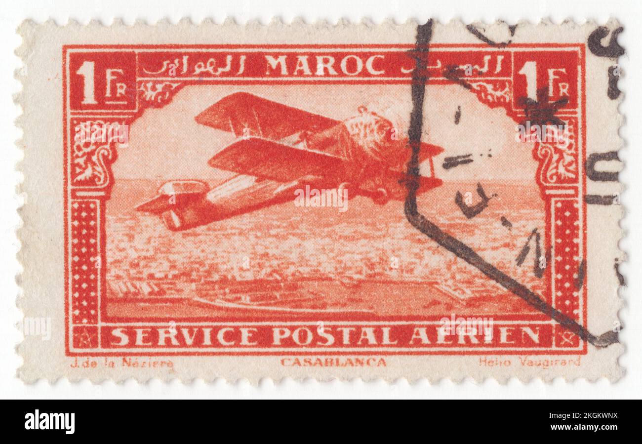 FRENCH MOROCCO - 1922: An 1 franc vermilion Air Post stamp depicting Biplane over Casablanca, (Dar al-Bayda), is the largest city in Morocco and the country's economic and business center. Located on the Atlantic coast of the Chaouia plain in the central-western part of Morocco, most populous city in the Maghreb region, and the eighth-largest in the Arab world. Casablanca is Morocco's chief port, with the Port of Casablanca being one of the largest artificial ports in the world, and the second largest port in North Africa, after Tanger-Med Stock Photo