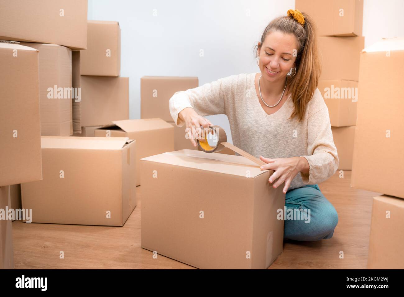 Young Caucasian girl packing boxes with duct tape Relocation concept