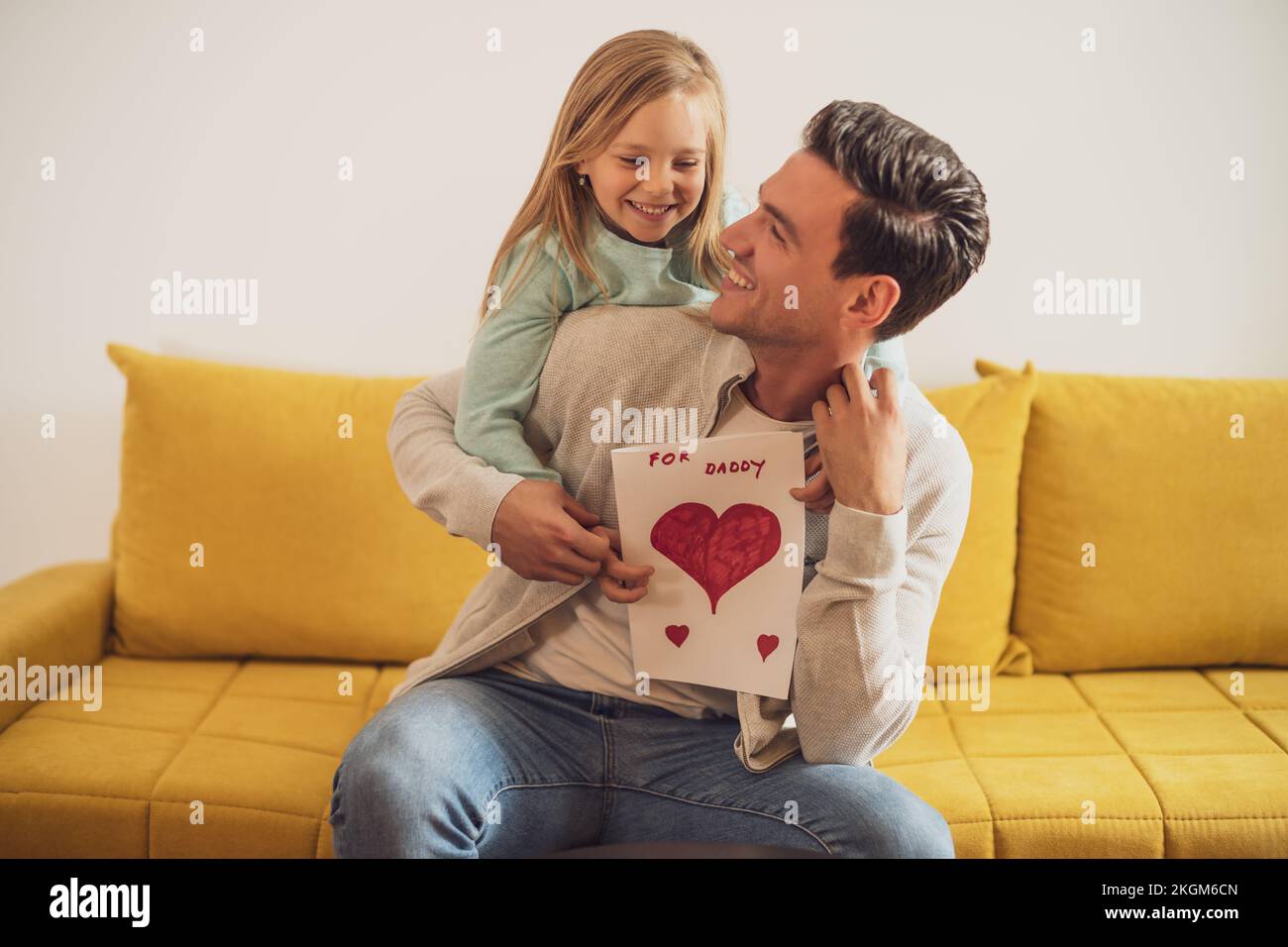 Happy father and daughter holding greeting card with heart shapes and ...