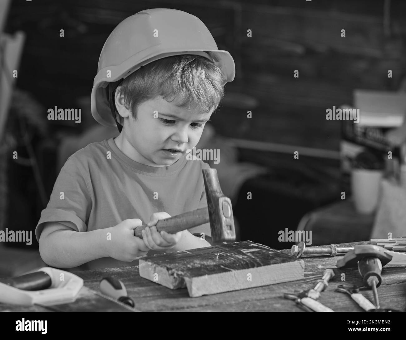 Concentrated kid working with hammer. Little boy gaining new skills