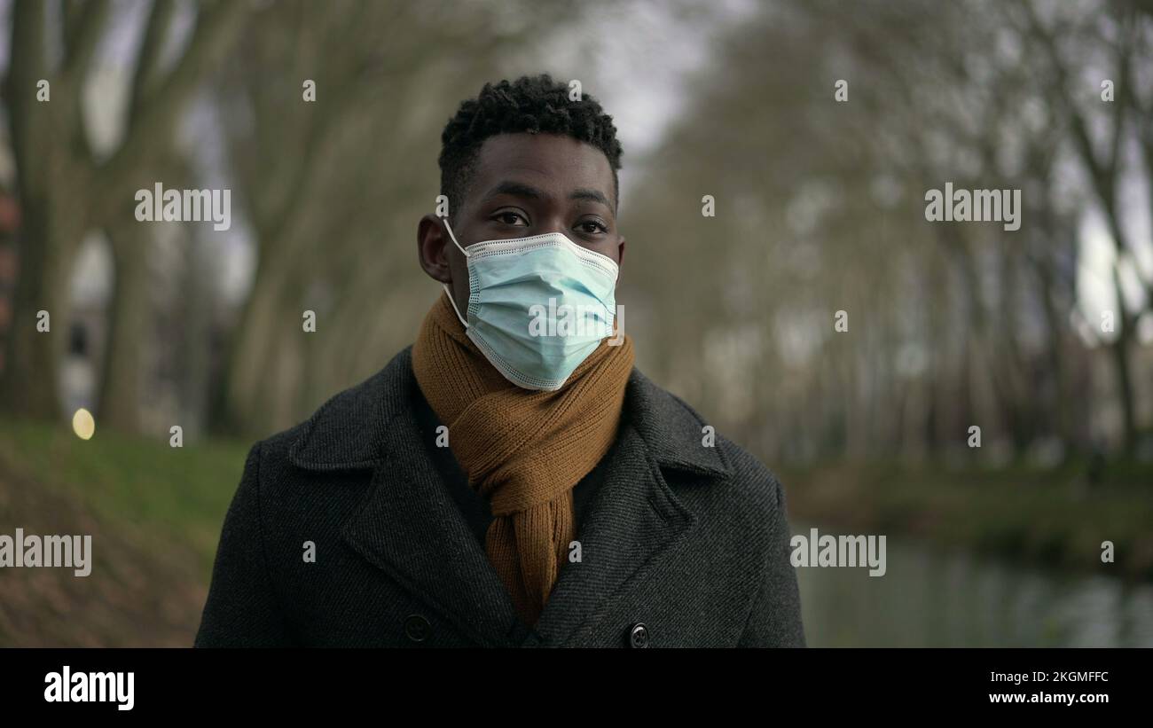 Young black man walking outdoors wearing surgical face mask Stock Photo ...