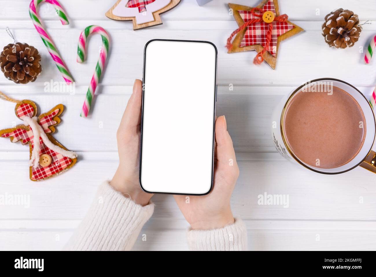 Close up woman holding phone with empty white screen mockup over decorated festive background, celebrating Christmas, customer shopping online, purcha Stock Photo