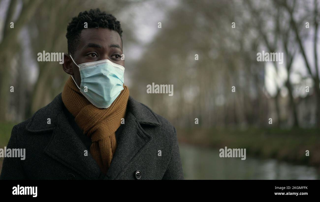 Young black man walking outdoors wearing surgical face mask Stock Photo ...