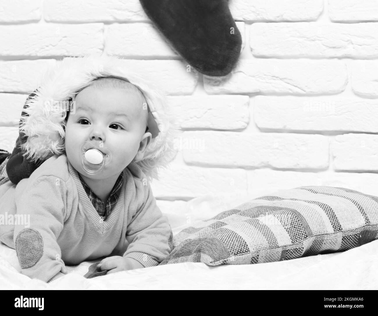 small baby boy with adorable curious face in yellow sweater laying on