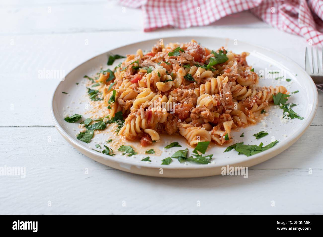 Tuna pasta with tomato sauce and parmesan cheese on a white plate isolated  on light background. Stock Photo
