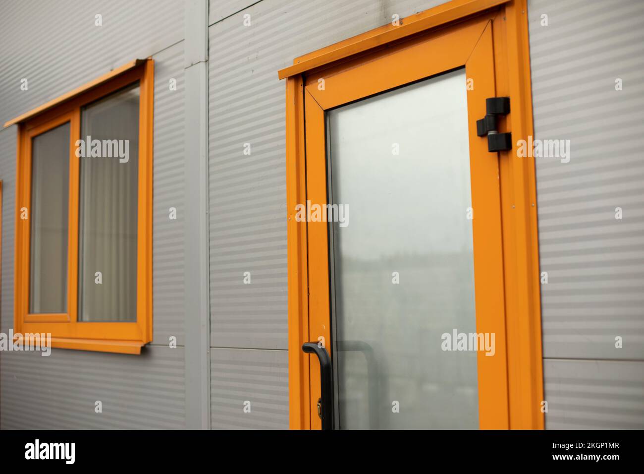 Orange door to building. Entrance to office. Door with glass. Grey ...
