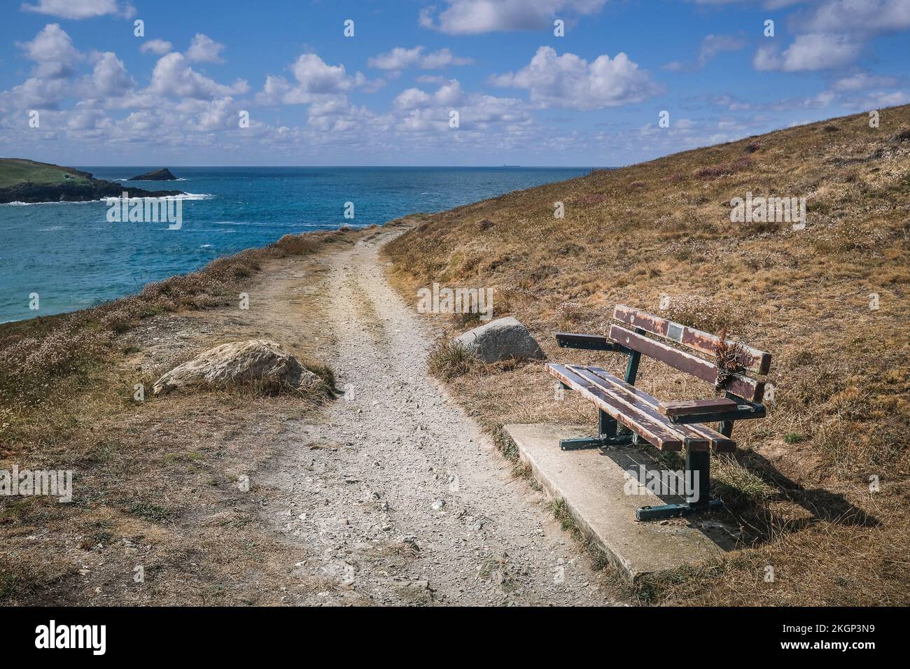 A bench on a rough footpath on the coast of Pentire Point East in Newquay in Cornwall in the UK. Stock Photo
