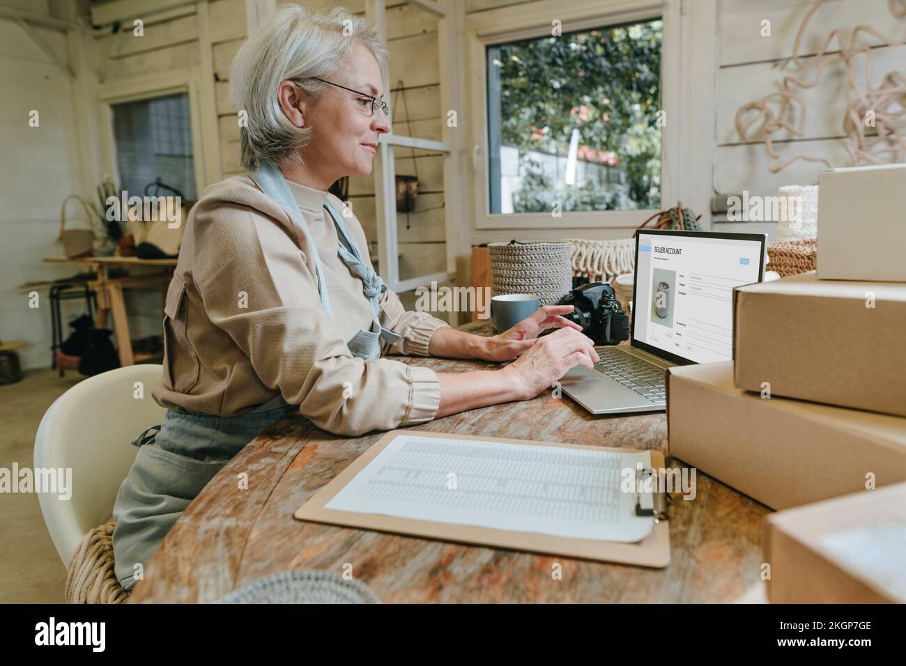 Craftswoman using laptop on workbench in workshop Stock Photo
