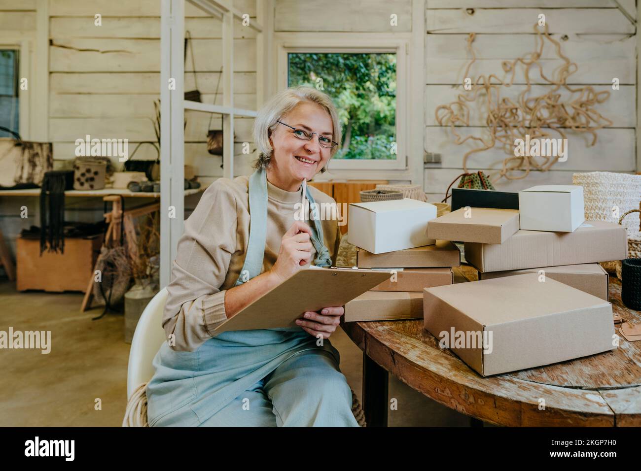 Happy craftswoman holding clipboard in workshop Stock Photo - Alamy