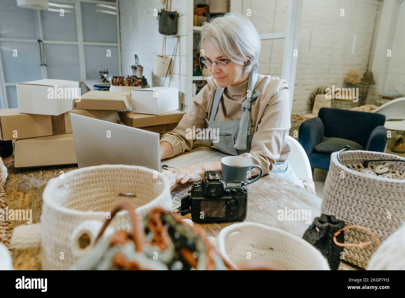 Craftswoman using laptop on workbench in workshop Stock Photo