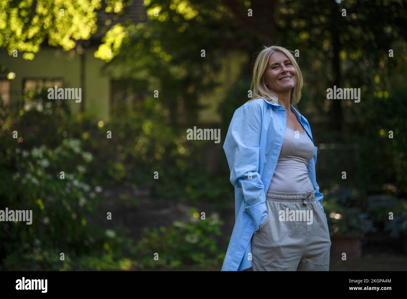 Happy mature woman standing with hands in pockets at garden Stock Photo ...