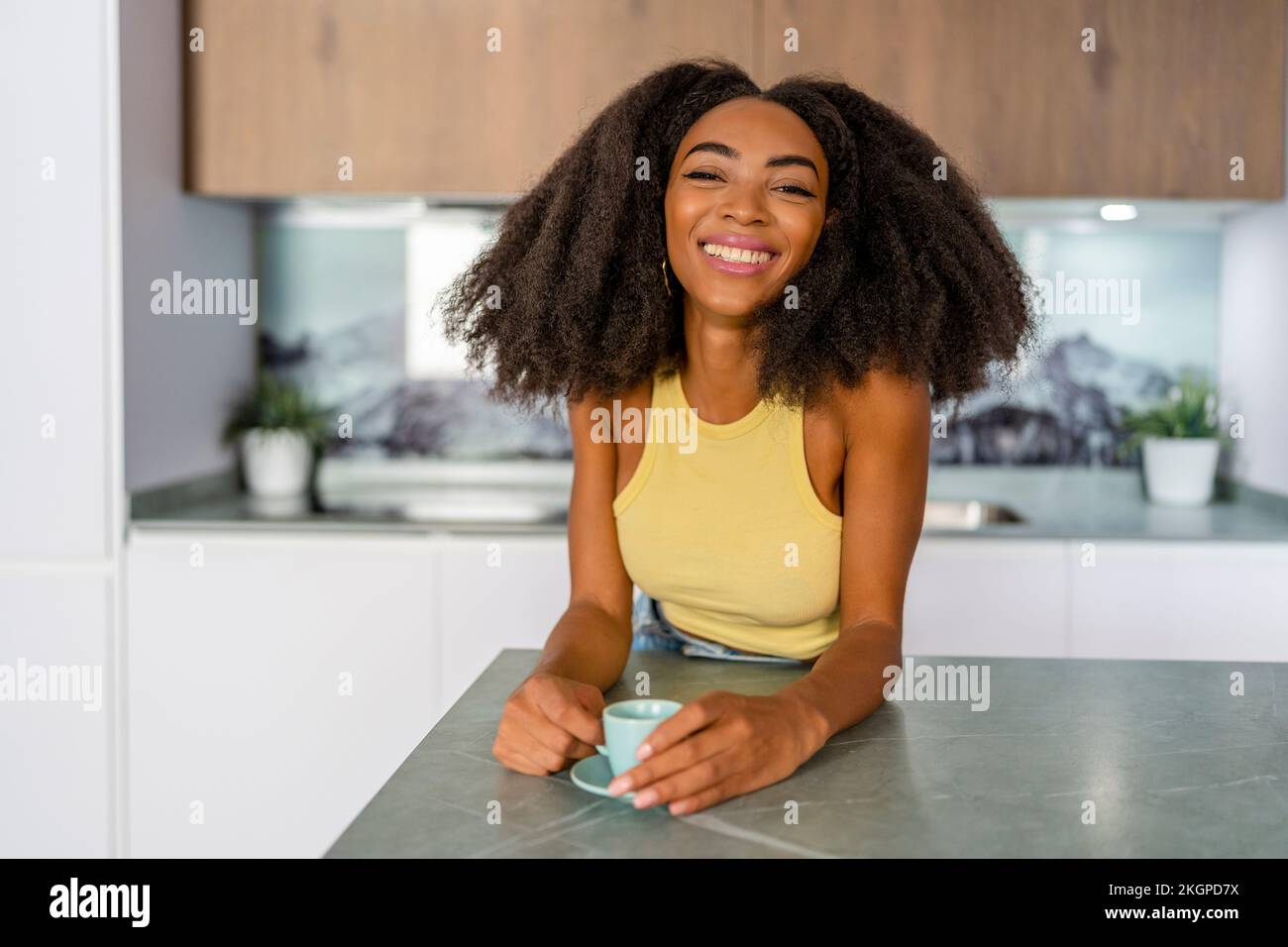 Happy Afro woman with coffee cup in kitchen Stock Photo