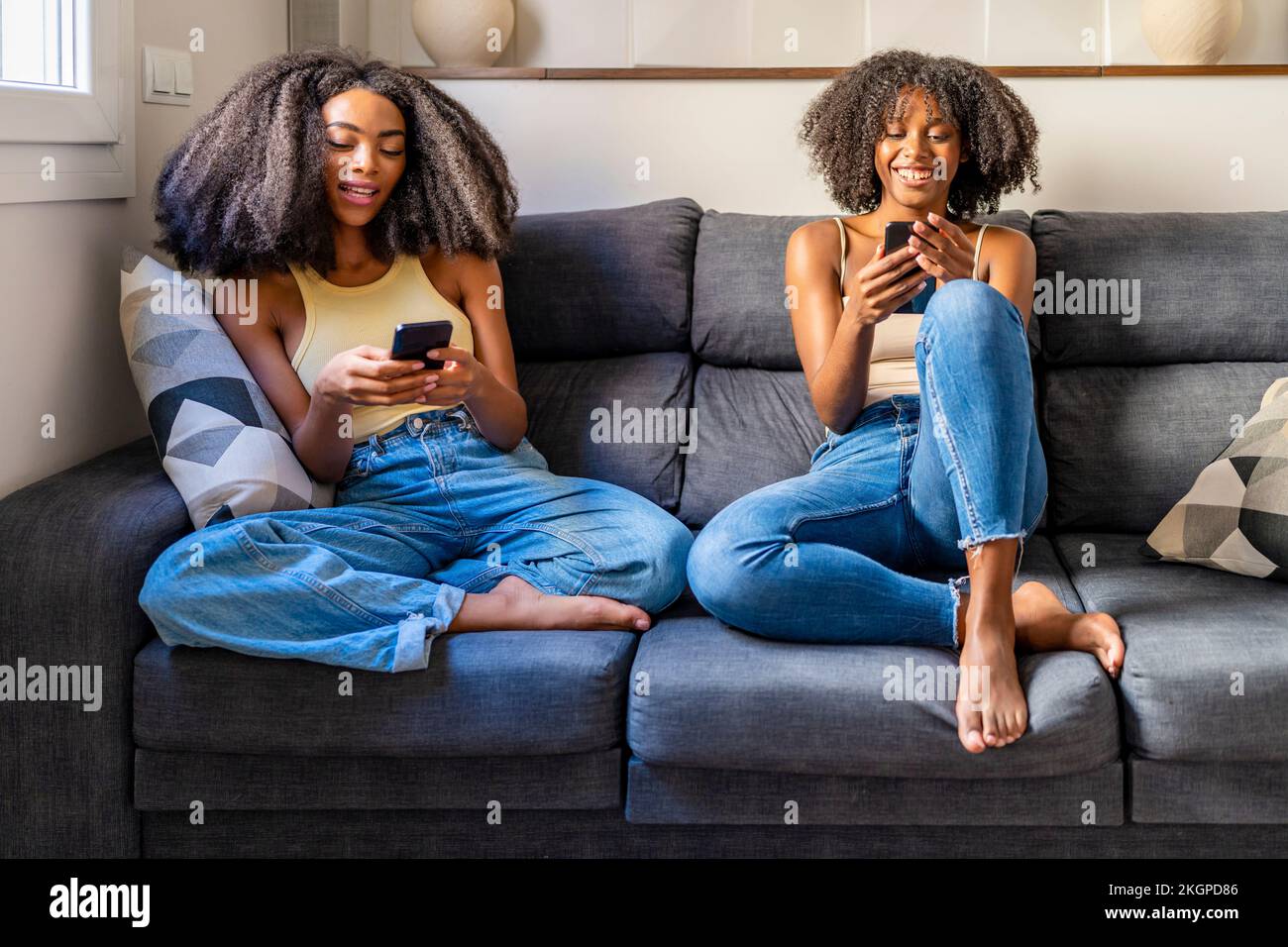 Young friends using smart phones sitting on sofa in living room Stock Photo